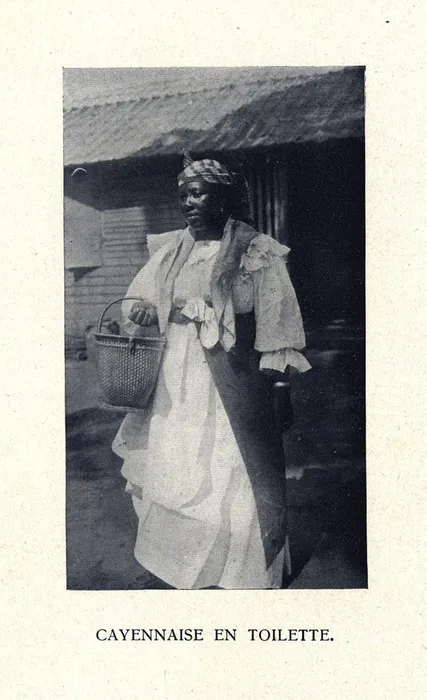 Photographie d'une Cayennaise debout vêtue d'un costume traditionnel et tenant un panier